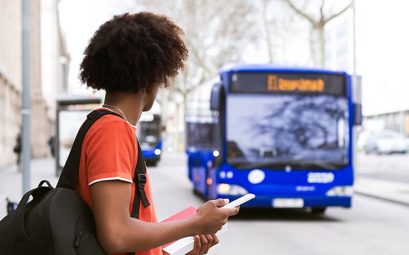 man waiting for a bus holding his phone